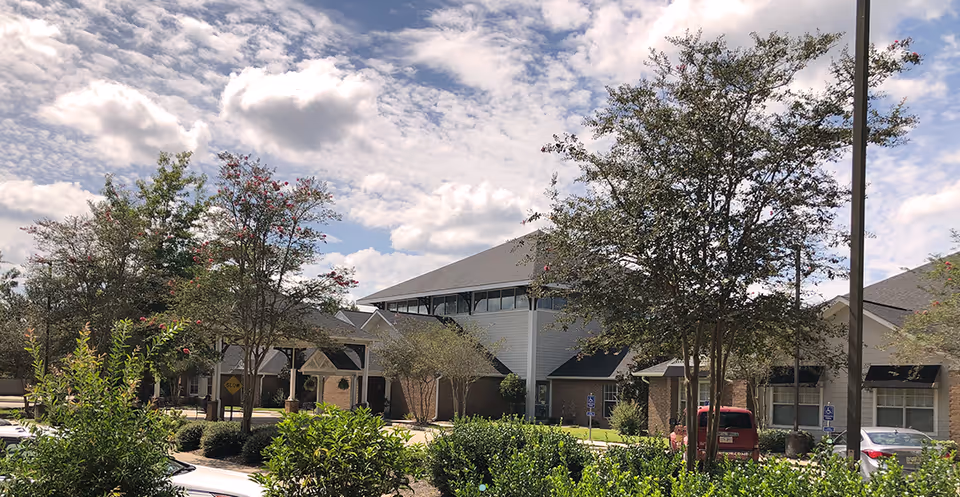 Exterior view of Oak Park Village at Slidell with cars and greenery.