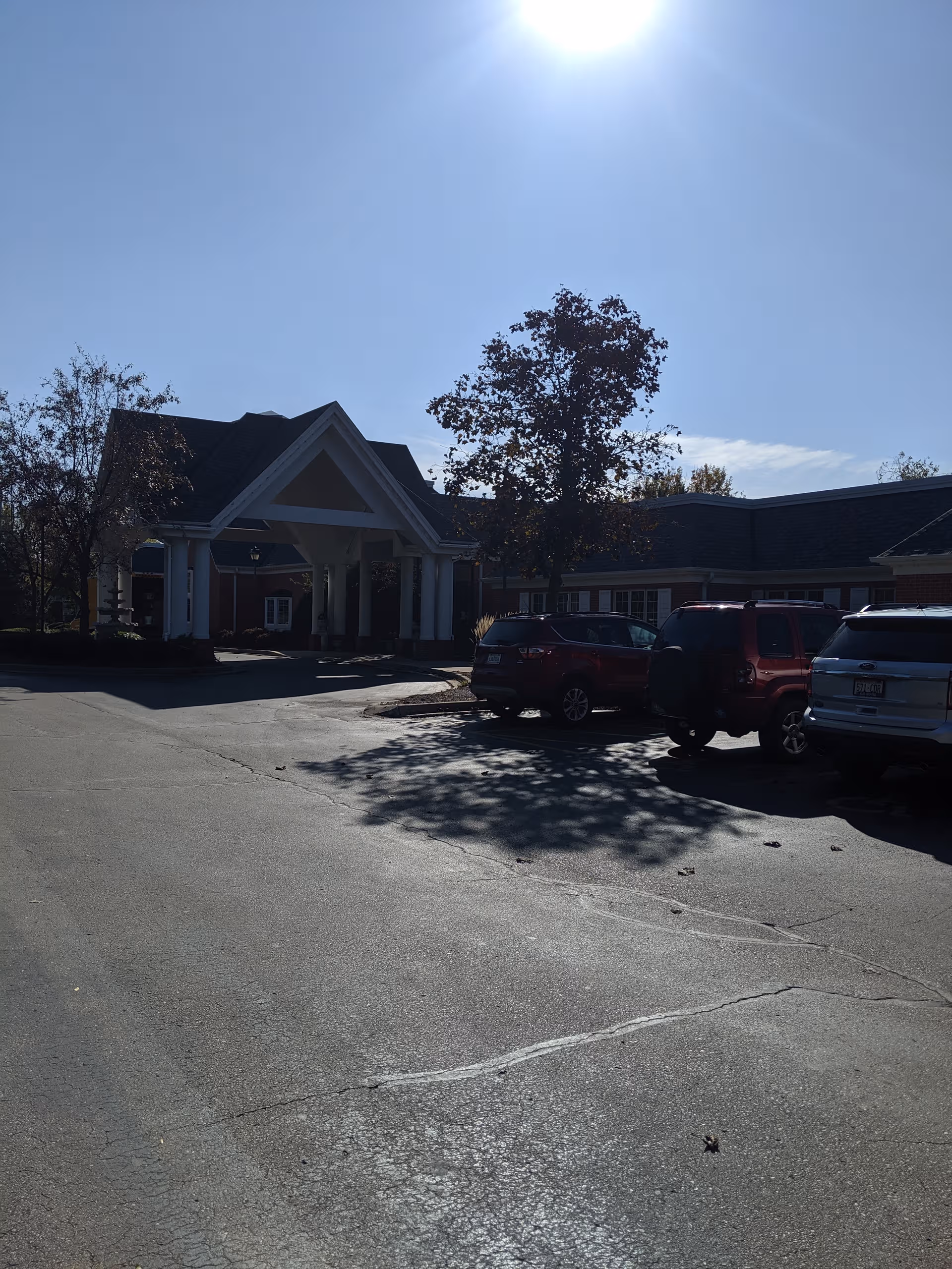 Senior living facility exterior with a covered entrance and parked cars.
