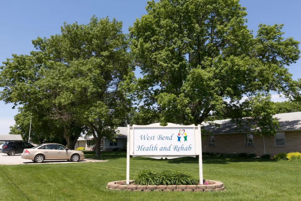 Exterior view of West Bend Health and Rehab with a sign and green lawn.