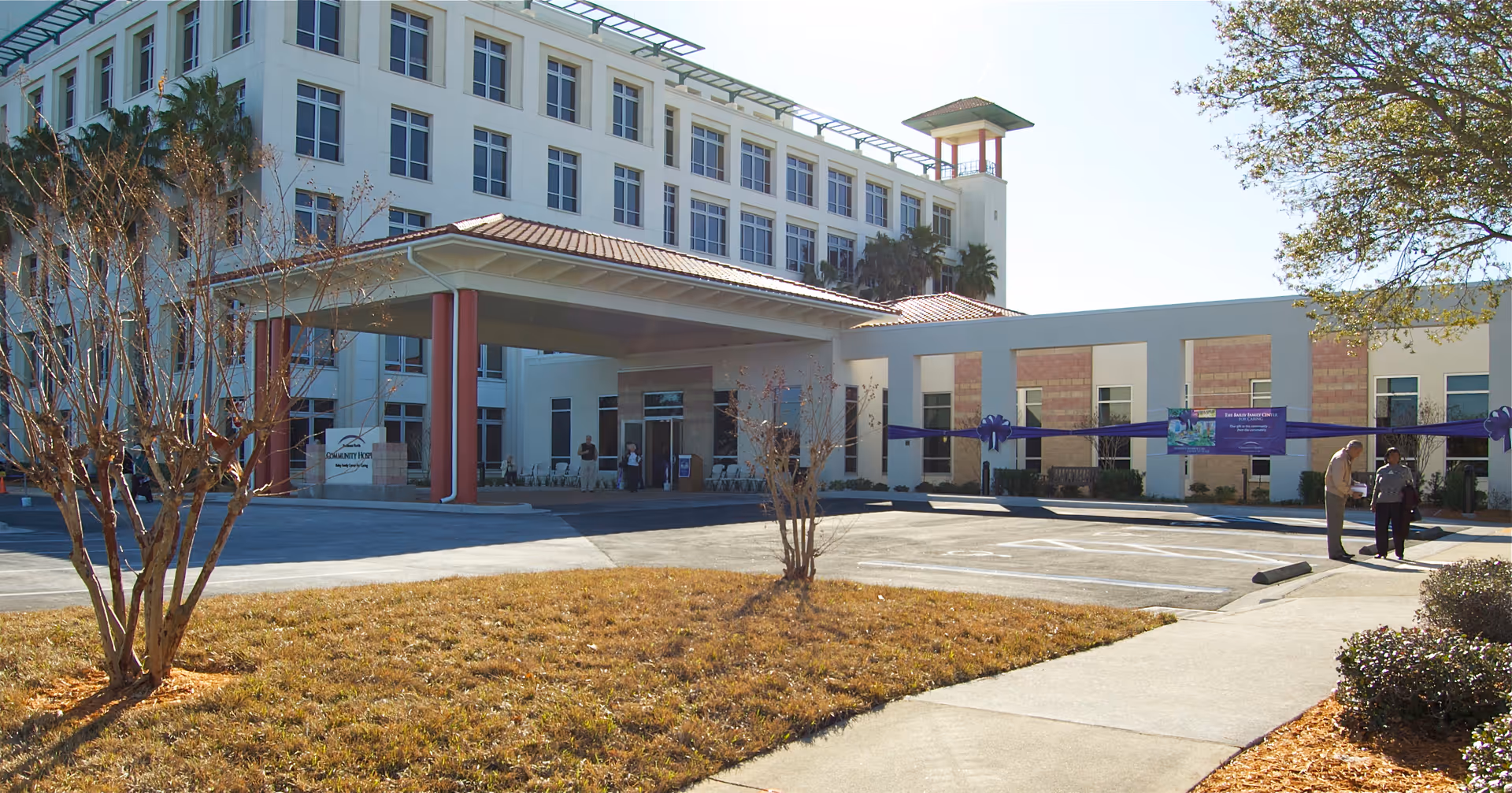 Exterior view of a multi-story hospice building with a covered entrance and parking lot.
