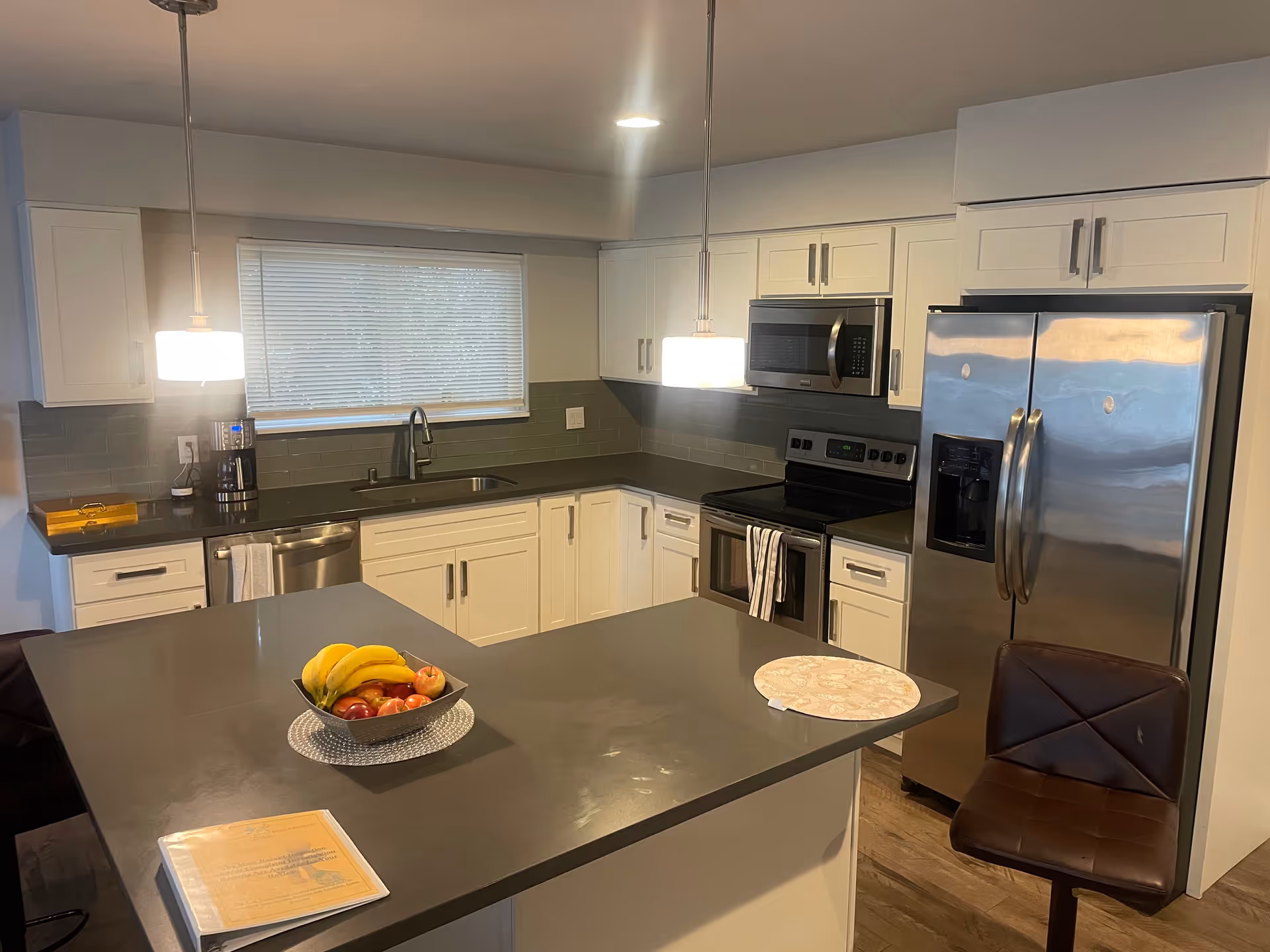 A modern kitchen in a senior living facility with an island and fruit bowl.