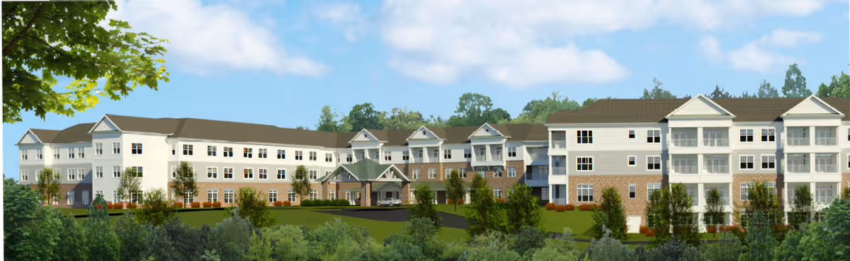 Panoramic exterior view of a three-story senior living building with a covered entrance, balconies, and landscaped grounds.