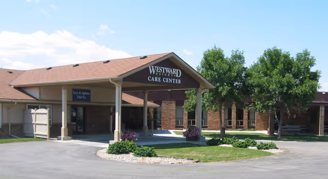 Front entrance of Westward Heights Care Center with a covered porte-cochère, driveway, and landscaped lawn with trees.