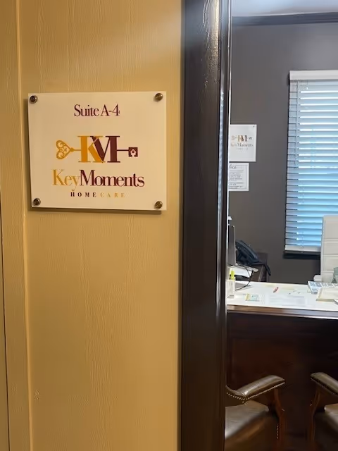 Interior doorway view showing Suite A-4 sign for Key Moments Home Care and an office desk.