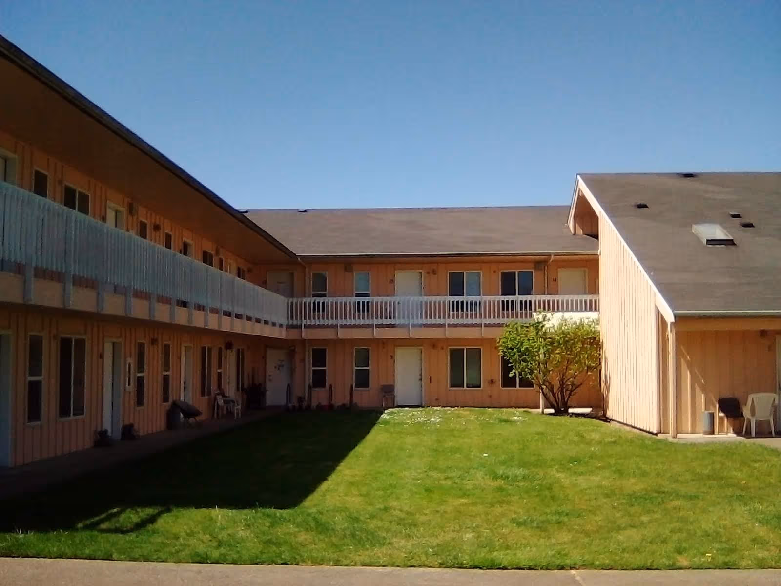 Two-story beige senior living building surrounds a grassy central courtyard.