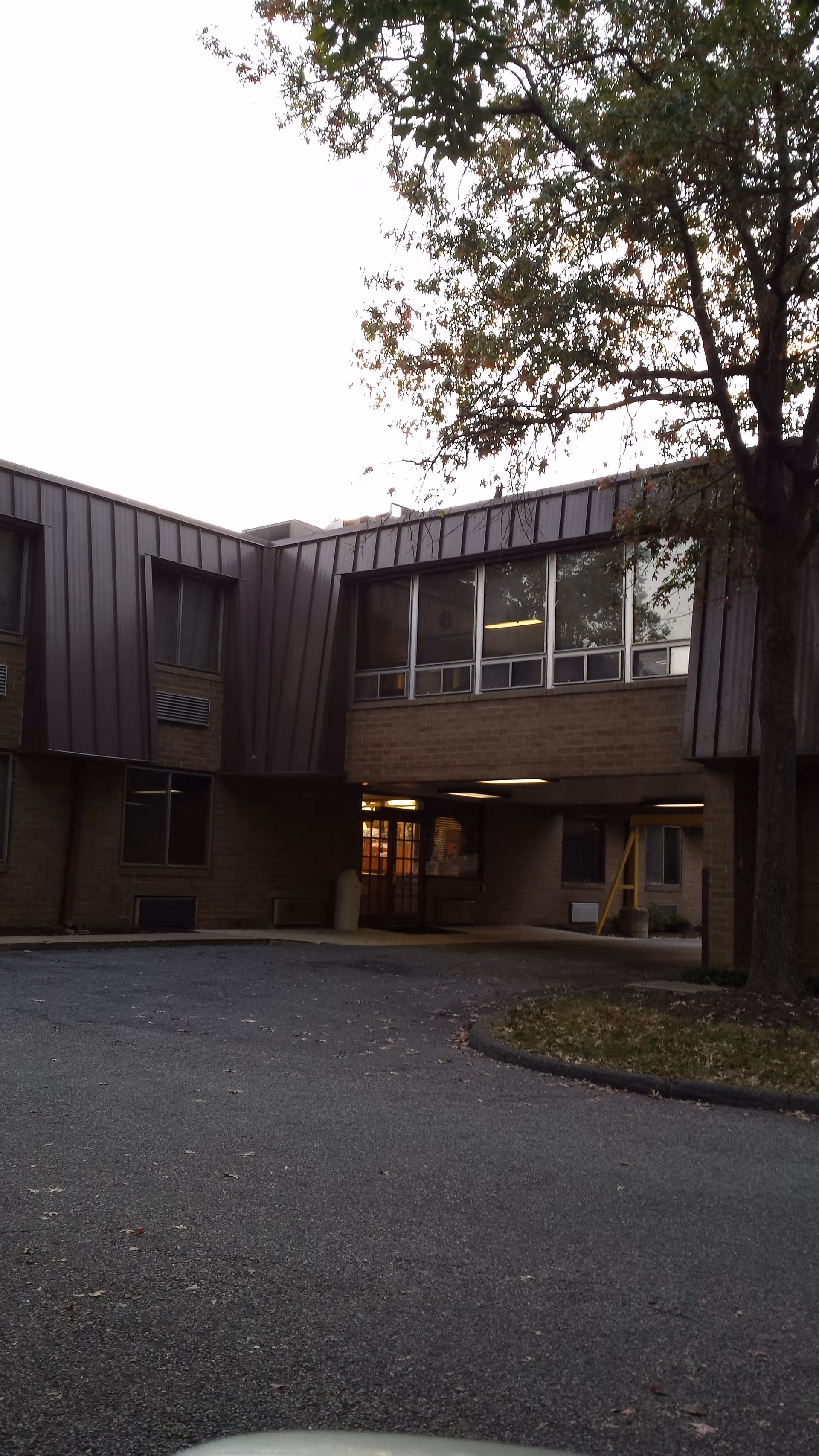 Exterior view of a brick nursing center with a tree and entrance.