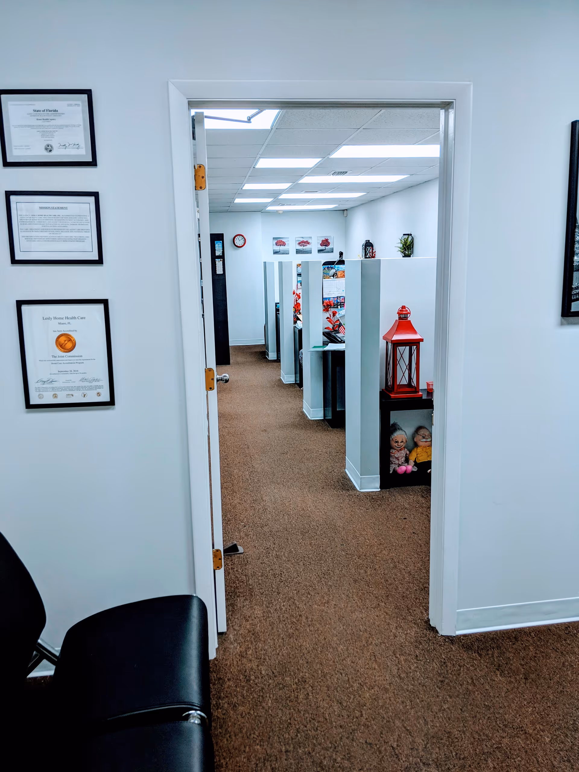 Interior hallway of a senior care office with cubicles and wall-mounted certificates.