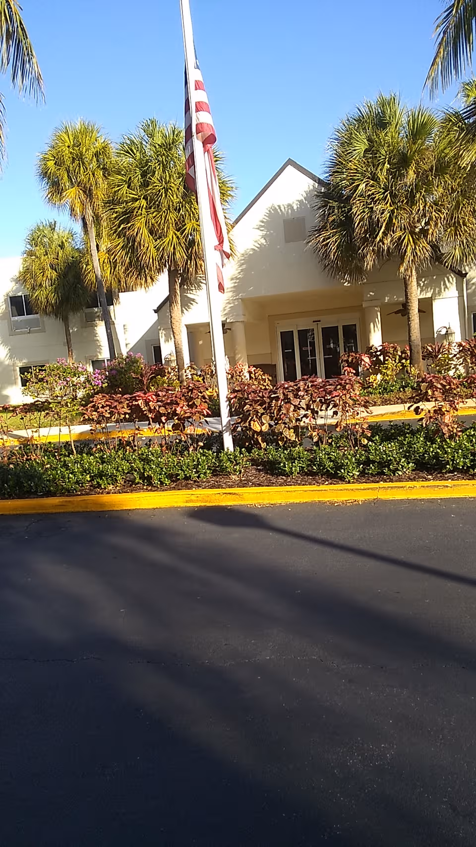 Front view of Palm Garden of Aventura entrance with palm trees and flagpole.