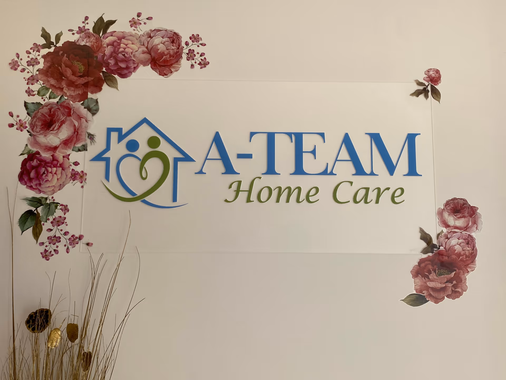 A-TEAM Home Care sign on an interior wall with pink floral border.
