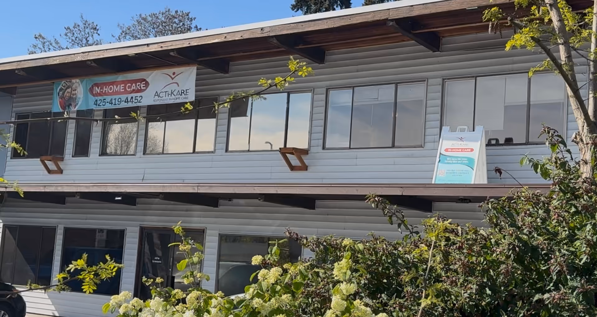 Two-story building exterior with Acti-Kare In-Home Care banners and windows