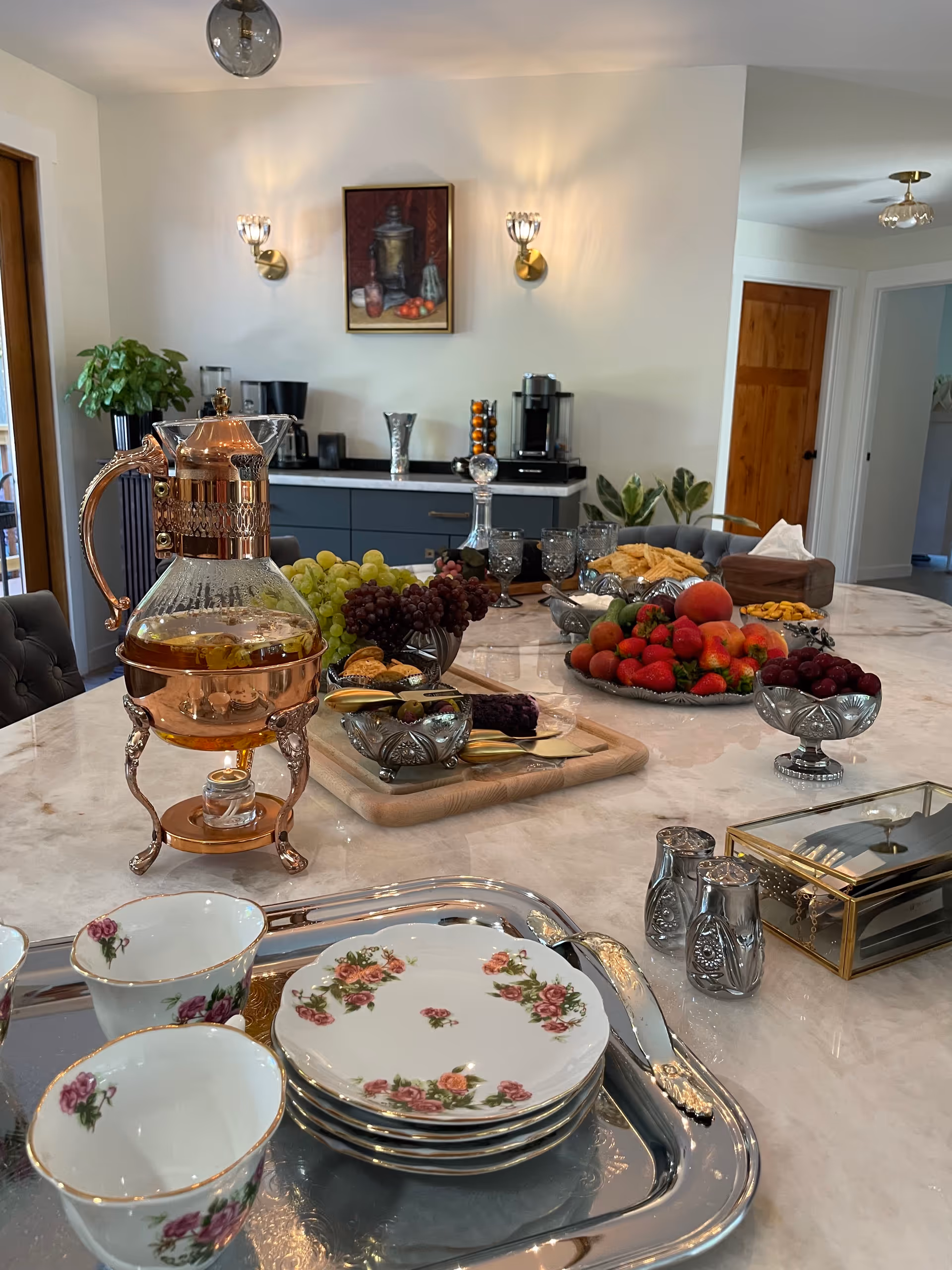 Marble dining table set with china, fruit, and beverages in a bright dining area.