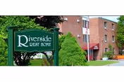 Riverside Rest Home sign beside a brick building and green landscaping