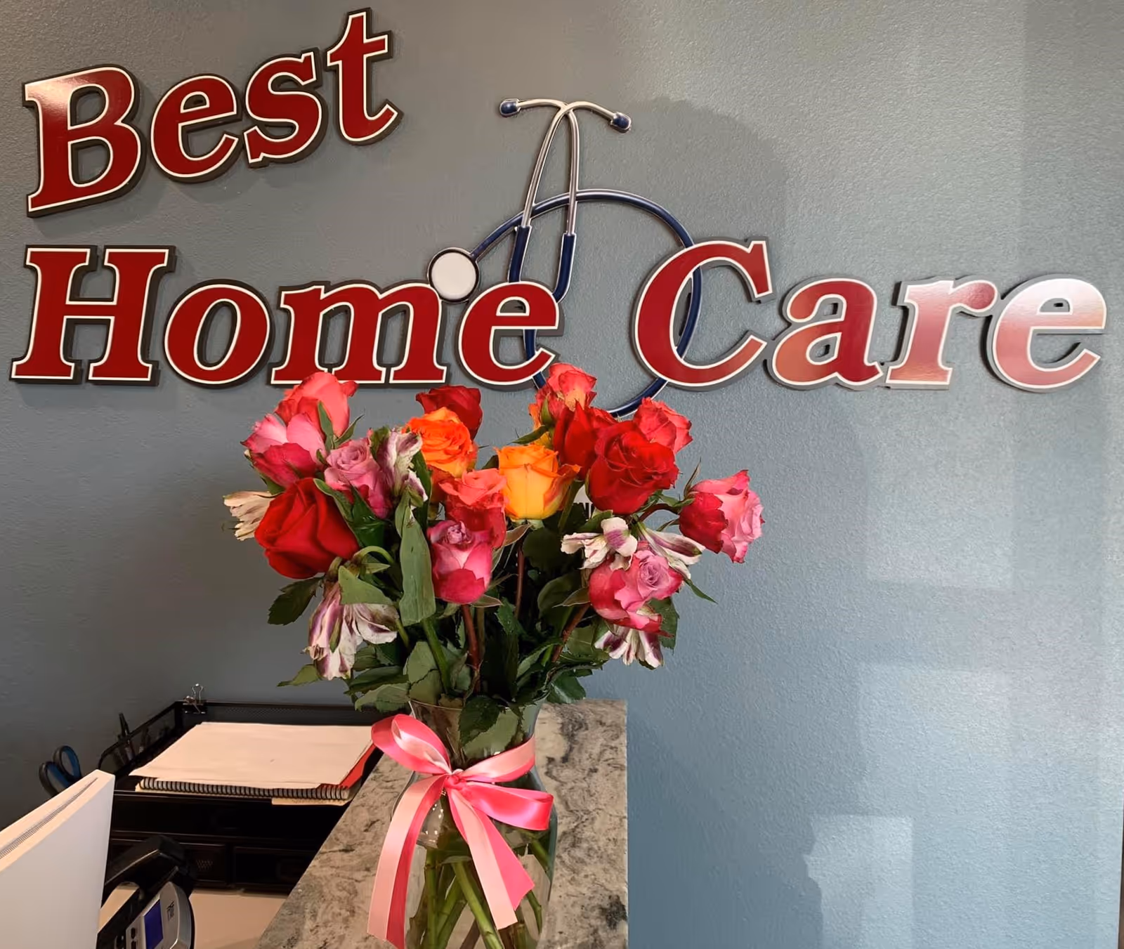 Lobby reception area with Best Home Care sign and colorful rose bouquet on desk