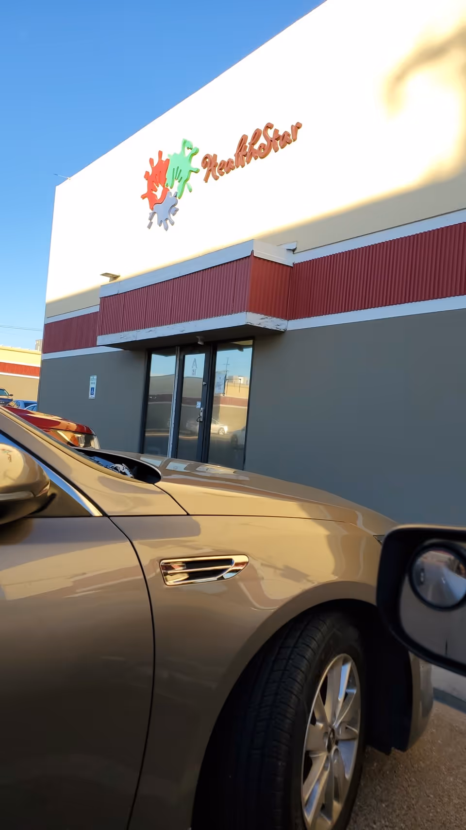 Front view of HealthStar Family Rehab Center building with a beige car parked outside.