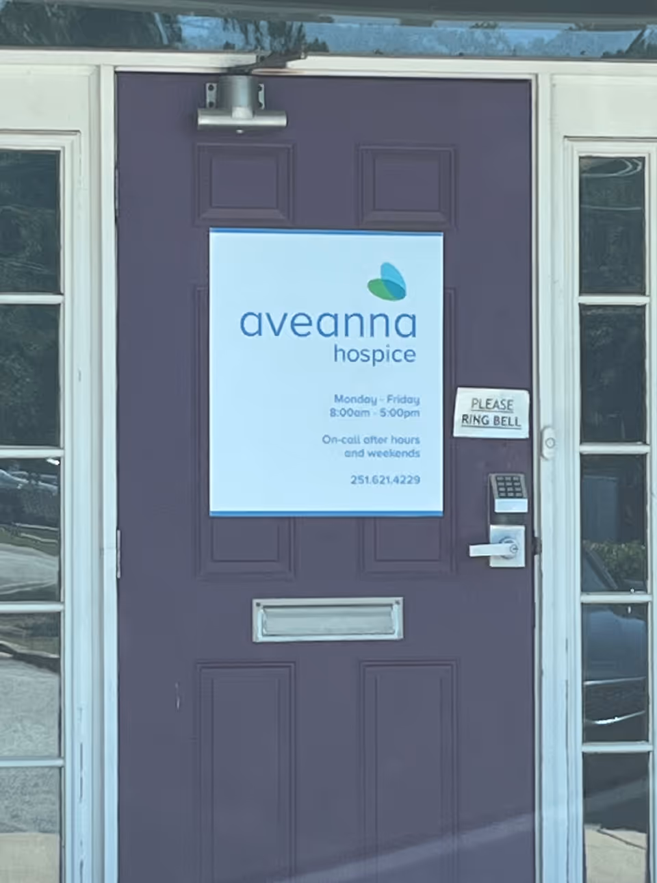 Purple front door with Aveanna Hospice sign and bell ring notice outside entrance.