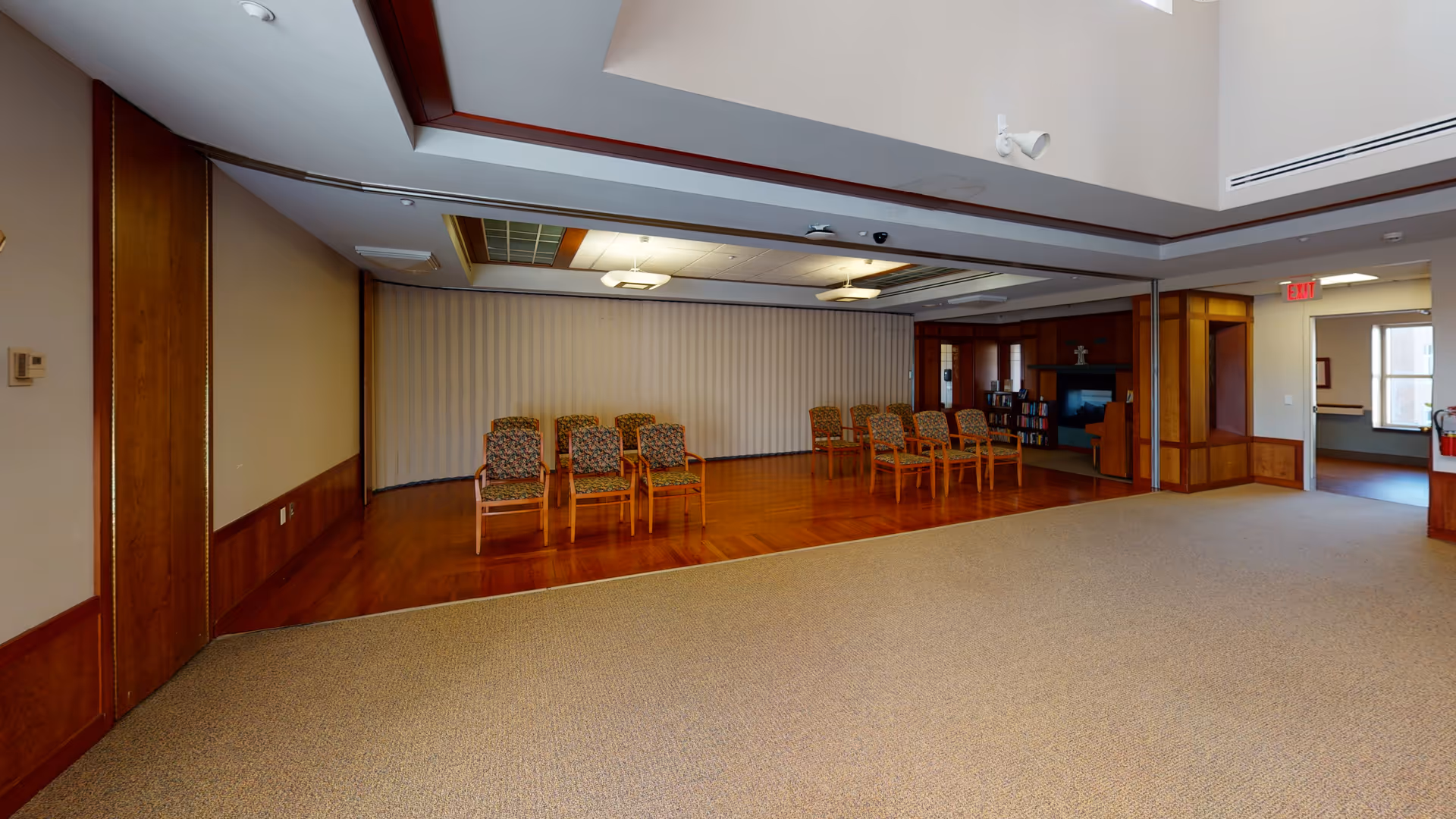 Spacious interior common area with beige walls, wood floors, and rows of chairs.