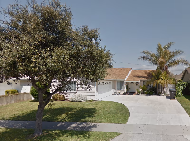 Front exterior of a single-story house with a curved driveway and lawn.