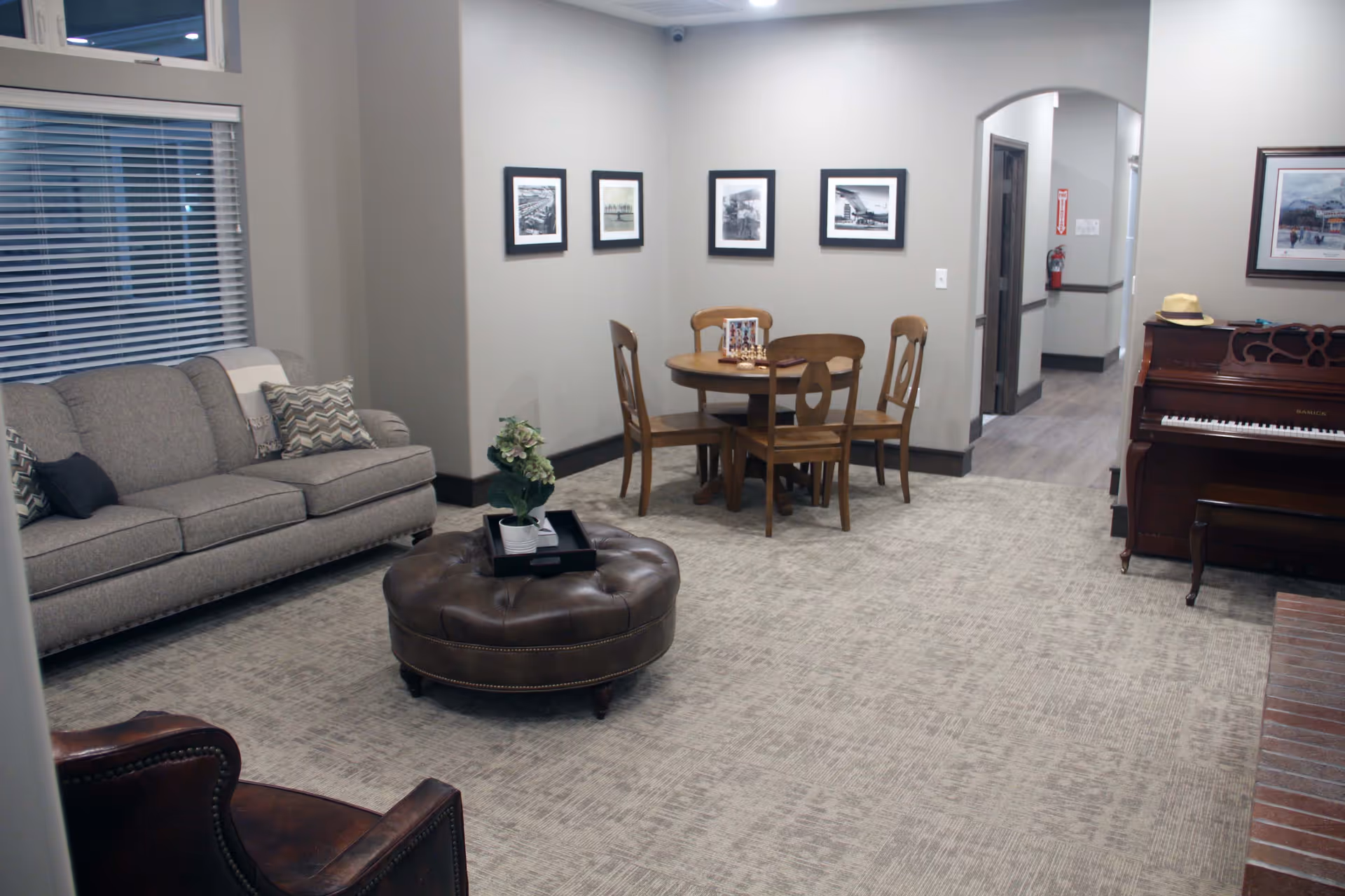 Common area at ComfortCare Homes - West with sofa, ottoman, dining table, and piano.