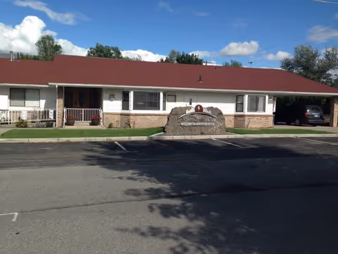 Single-story facility with red roof, stone sign, and parking lot in front.