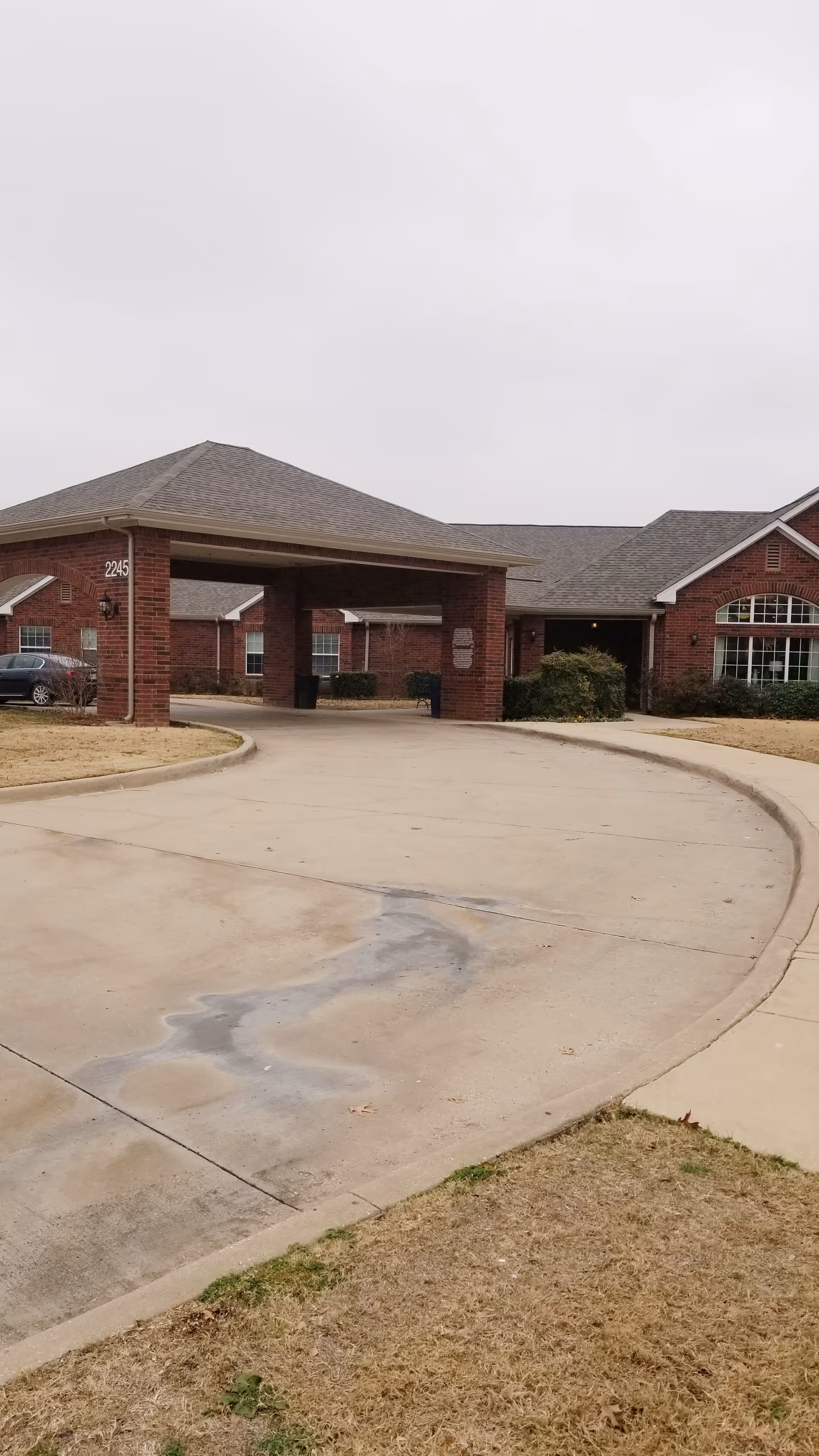 Brick senior living facility with a covered entrance and curved driveway.