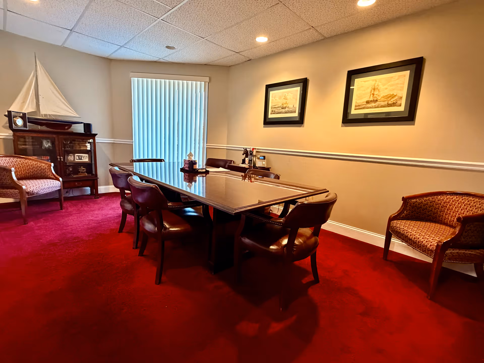 Conference-style meeting room with a long table, chairs, and nautical decor.