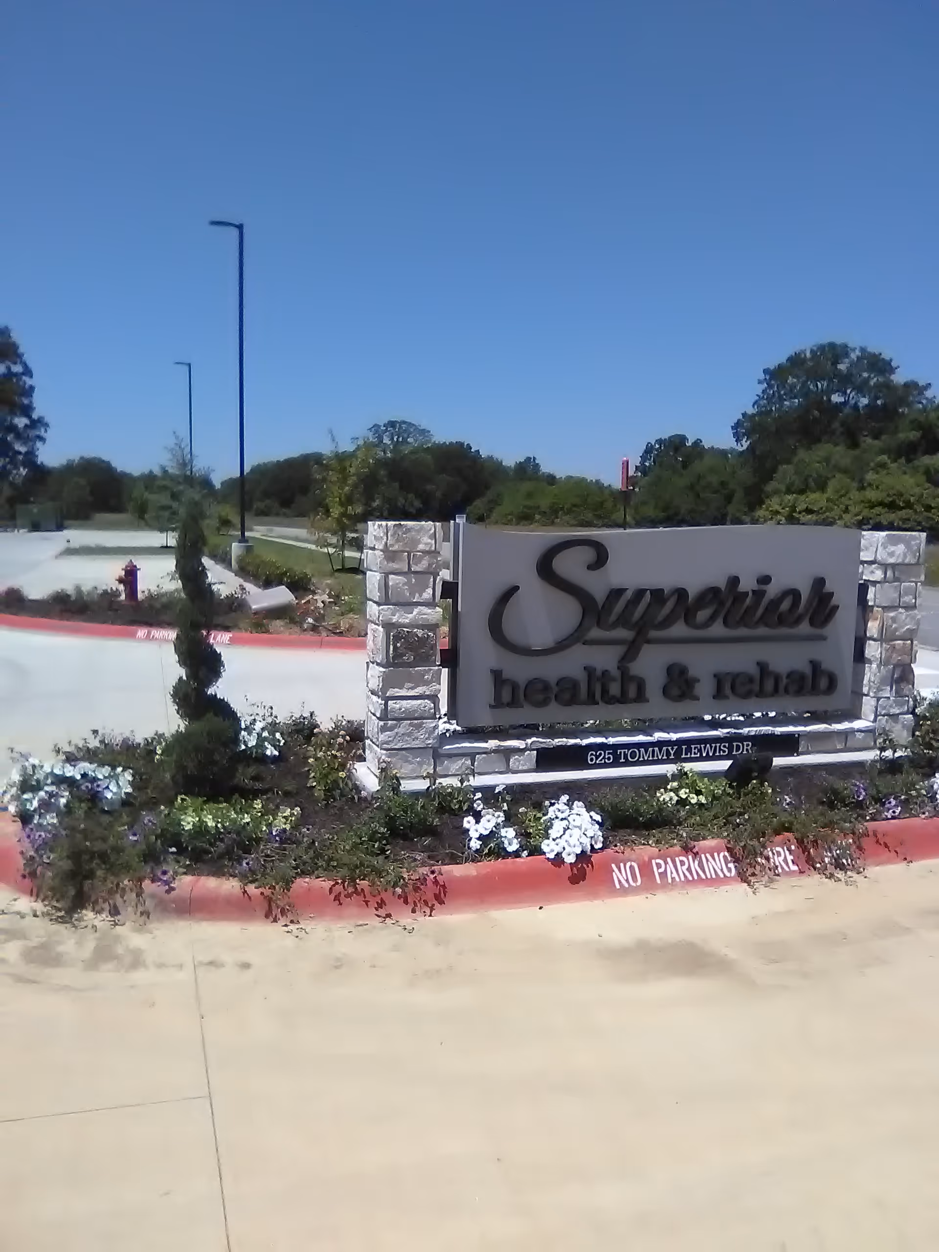 An exterior facility sign reading Superior Health and Rehab, surrounded by landscaping and a blue sky.
