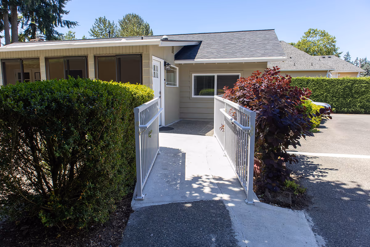 Front exterior of a single-story senior living facility with a ramp entrance.