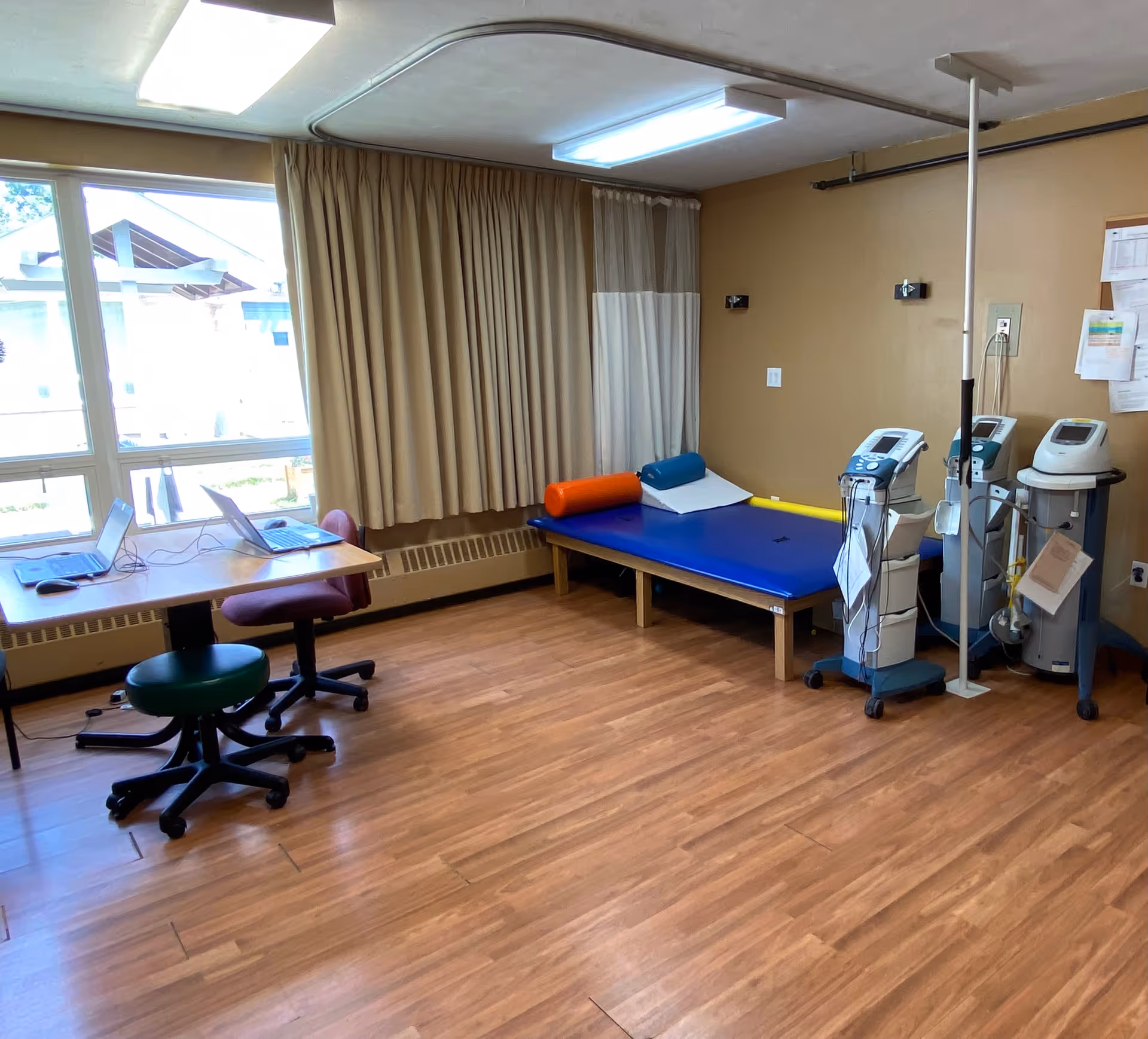 Therapy room in a senior facility with a treatment bed, curtains, and medical devices.