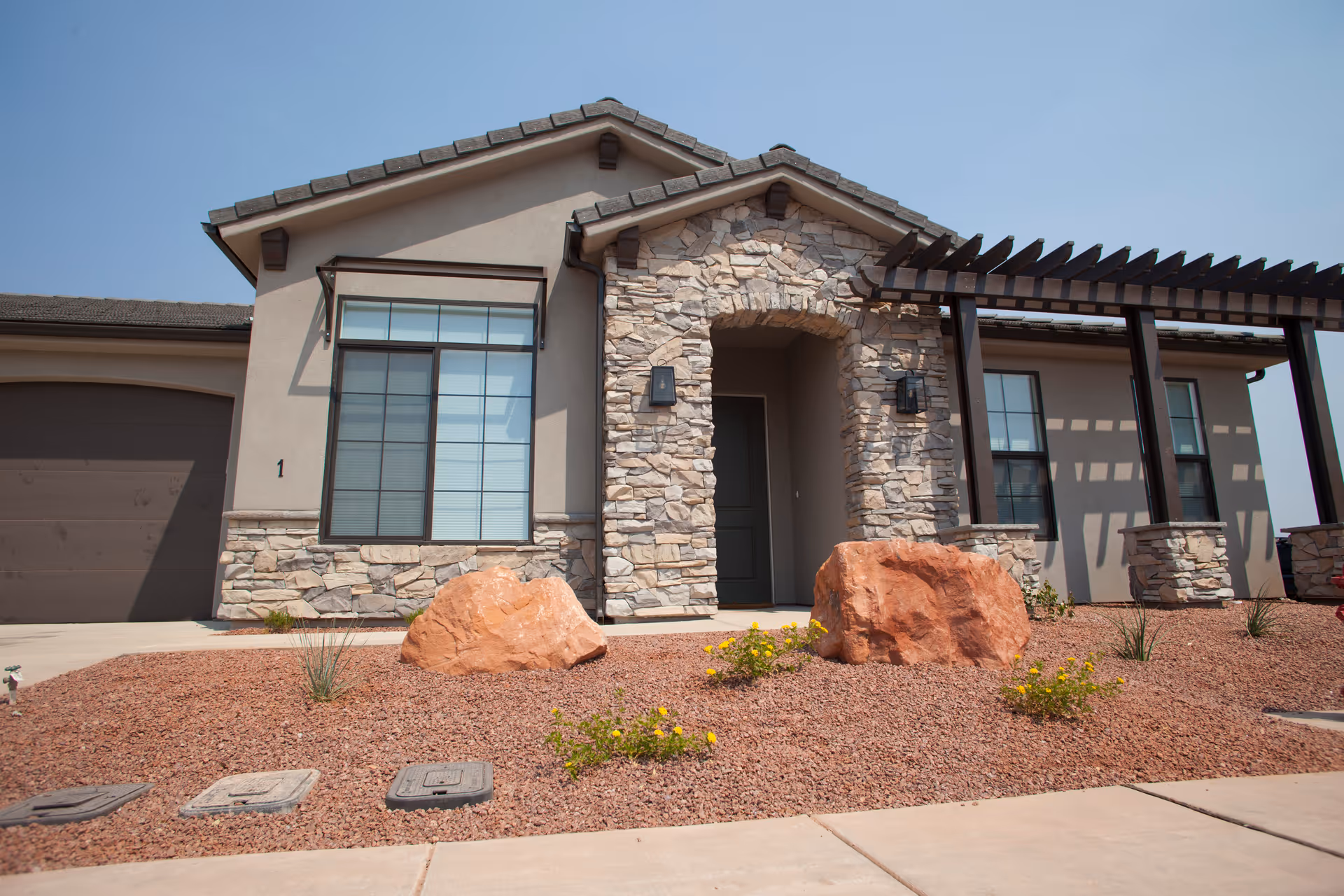 Modern stone facade senior living facility entrance with a covered walkway and desert landscaping.