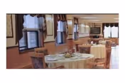 A bright dining room with round tables set for meals in a senior facility.