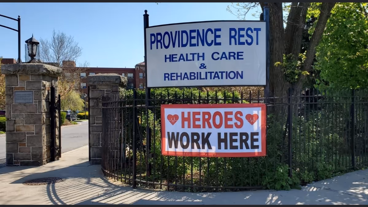 Entrance to Providence Rest Health Care & Rehabilitation with a gate and banners.