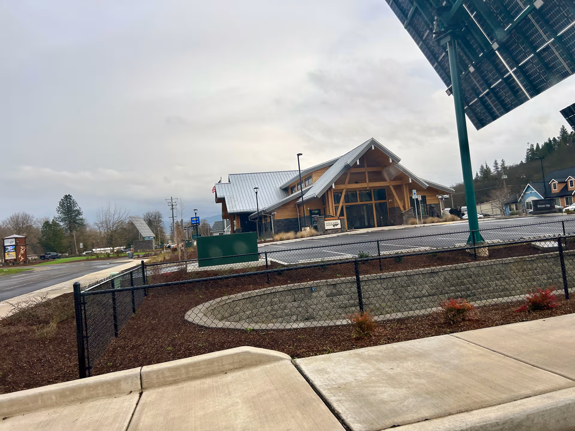 Modern wooden-facade senior living center entrance with solar panels and landscaped surroundings.