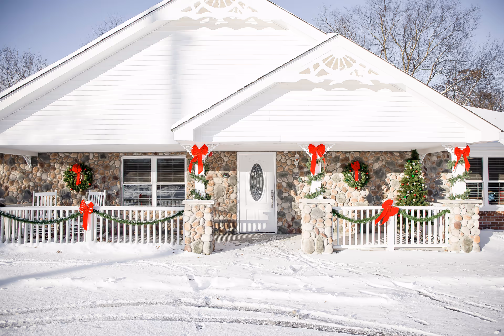 Snowy exterior of a decorated senior care facility with wreaths, garlands, and a Christmas tree.