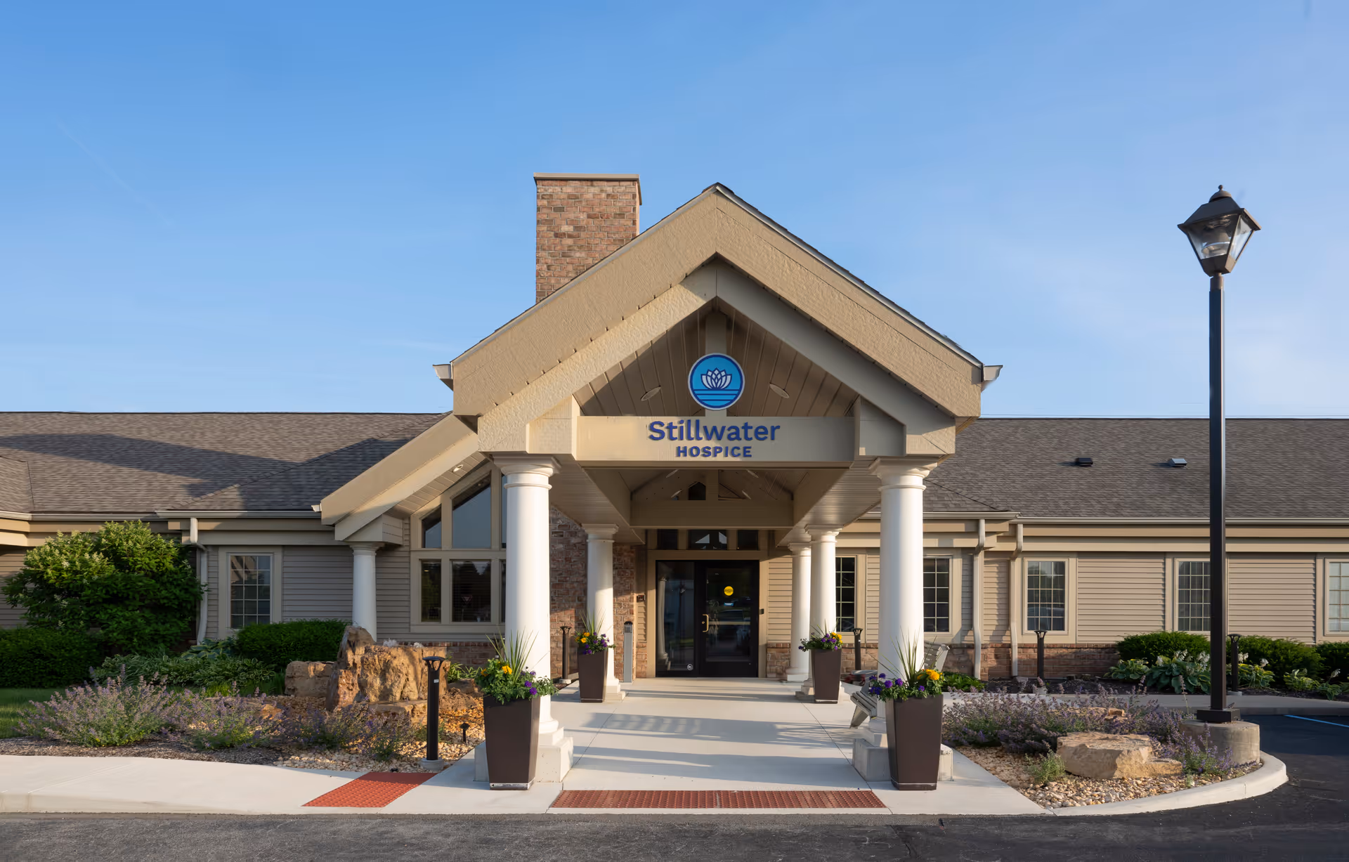 Front exterior of Stillwater Hospice building with columns and landscaping.