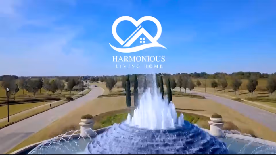 Logo for Harmonious Living Home over fountain, road, and trees in an outdoor landscape.