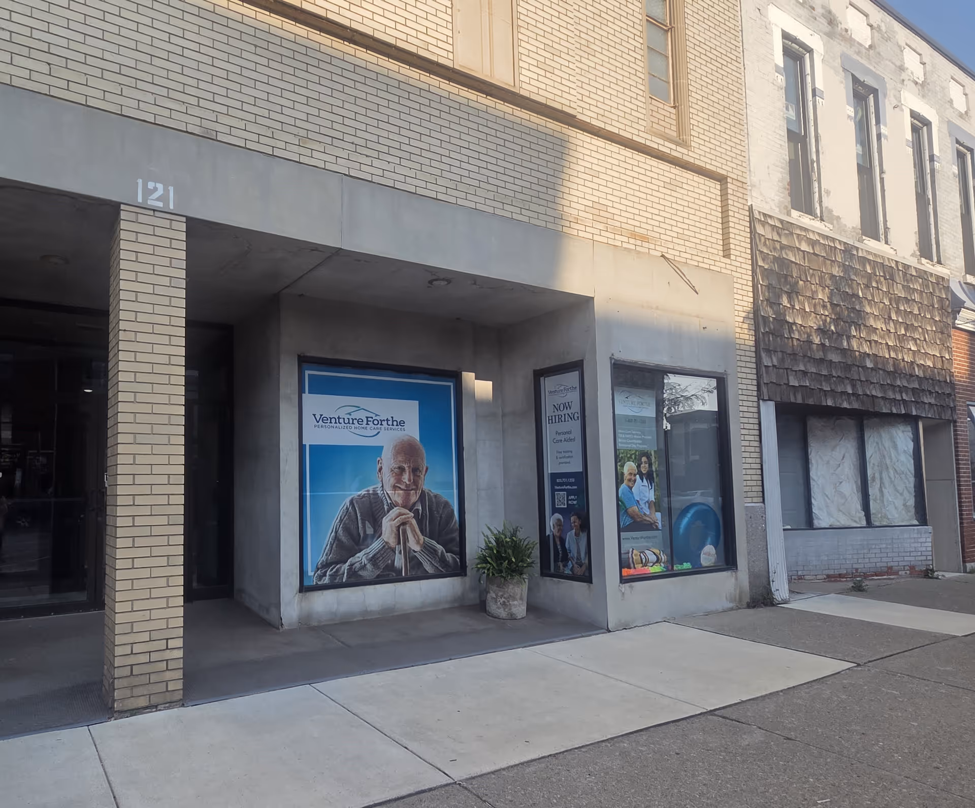 Exterior storefront with Venture Forthe signage and large elderly care posters.