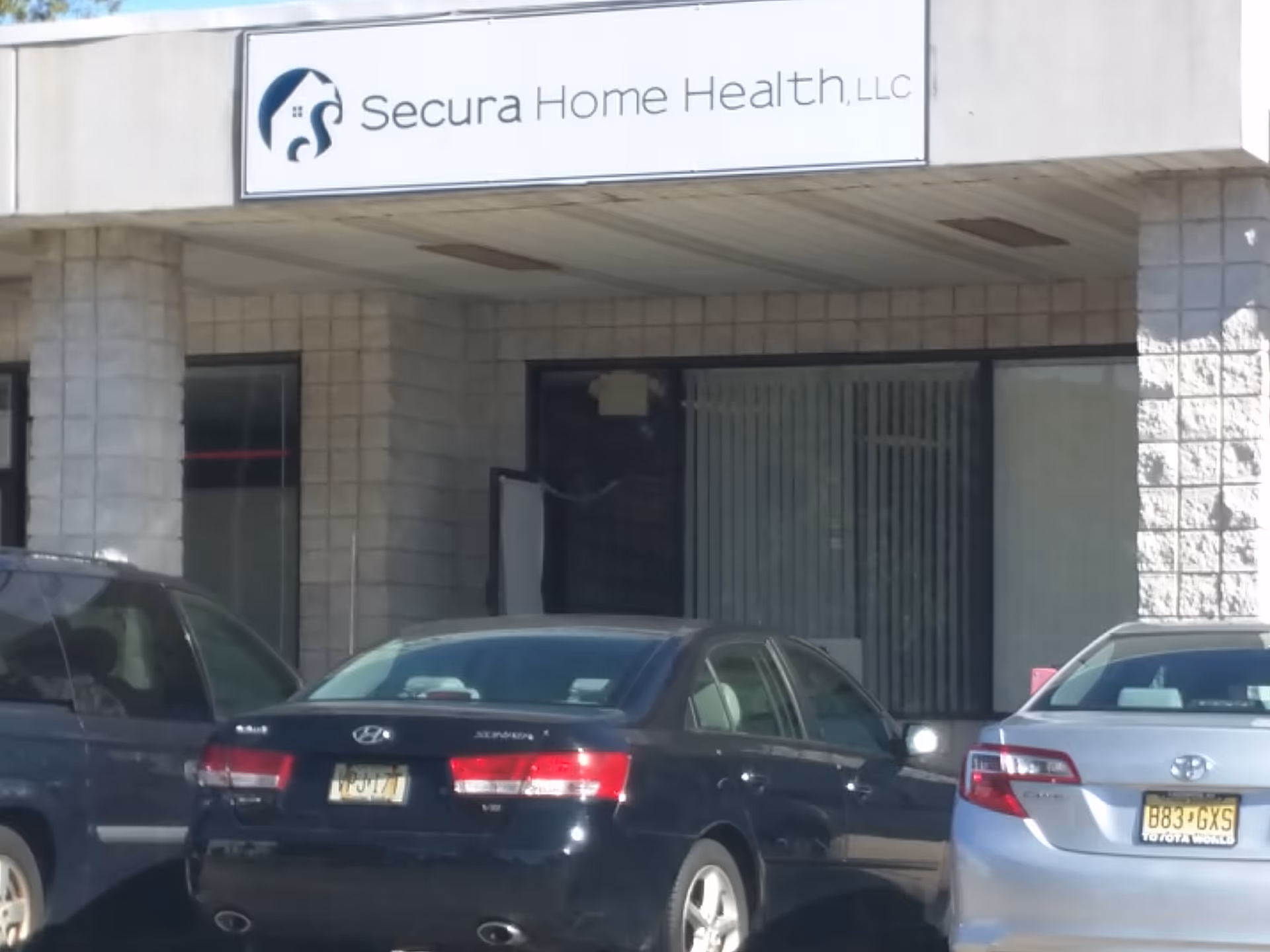Exterior view of Secura Home Health, LLC storefront with parked cars in front.