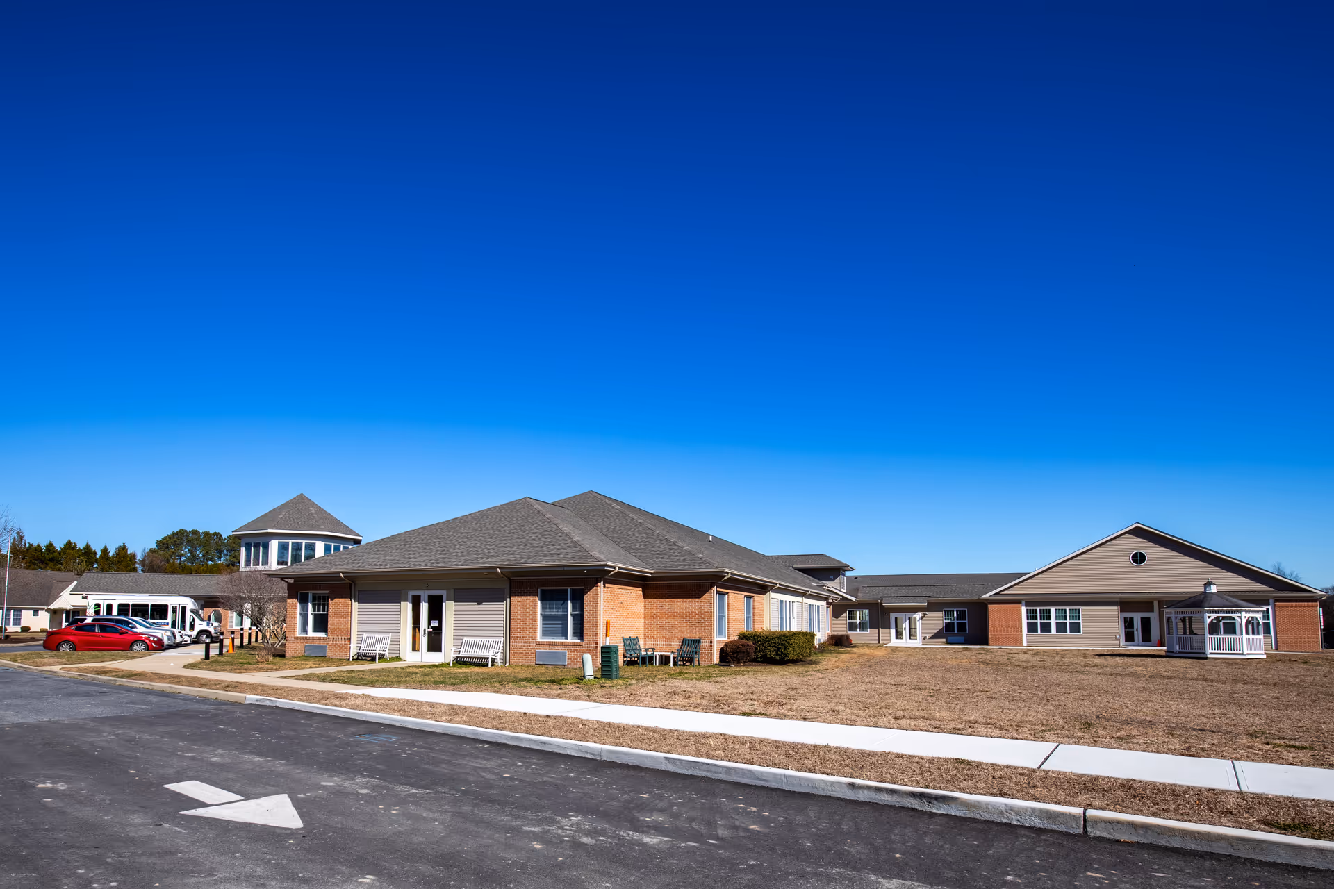 Single-story brick senior living facility with a peaked roof and clear blue sky.