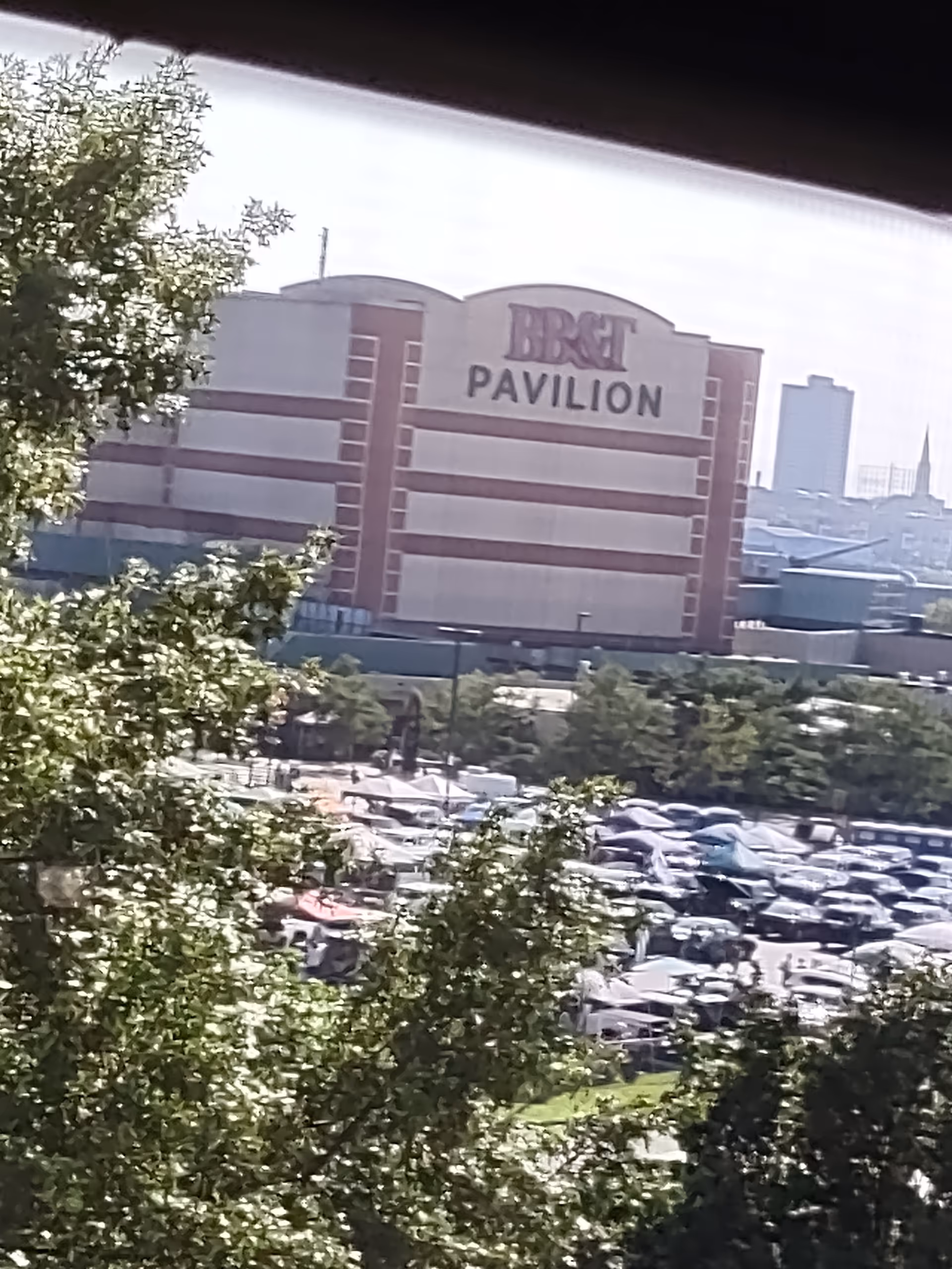 Exterior view of a pavilion-style building with a parking lot and trees.