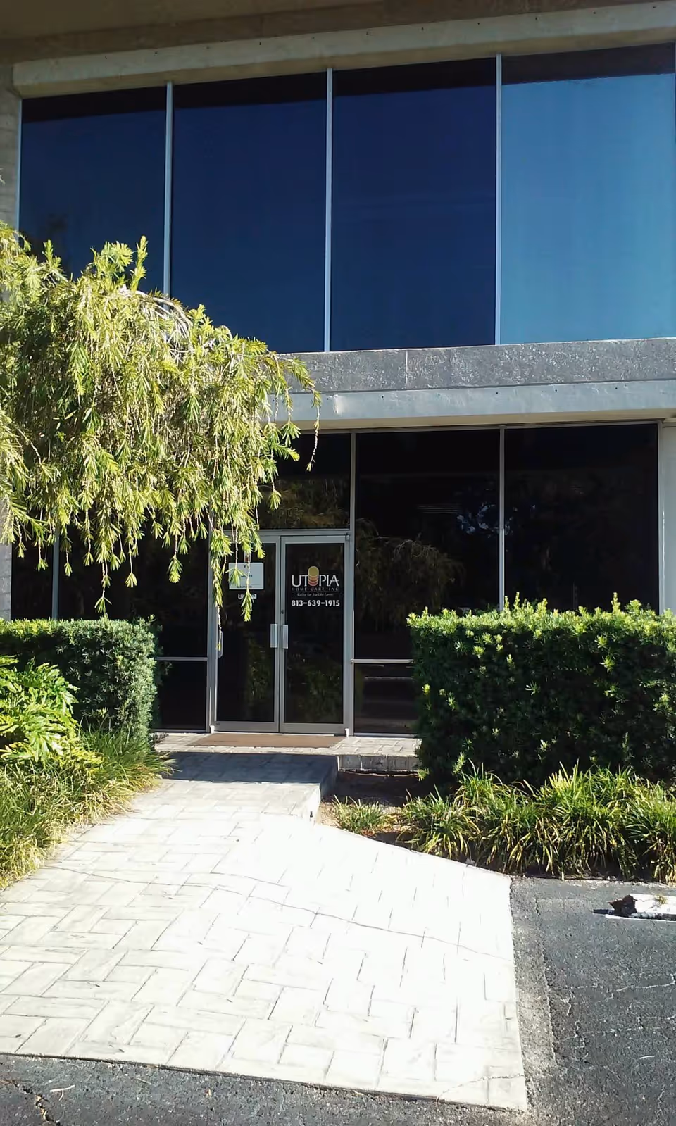 Front entrance of a modern building with glass doors and surrounding landscaping.