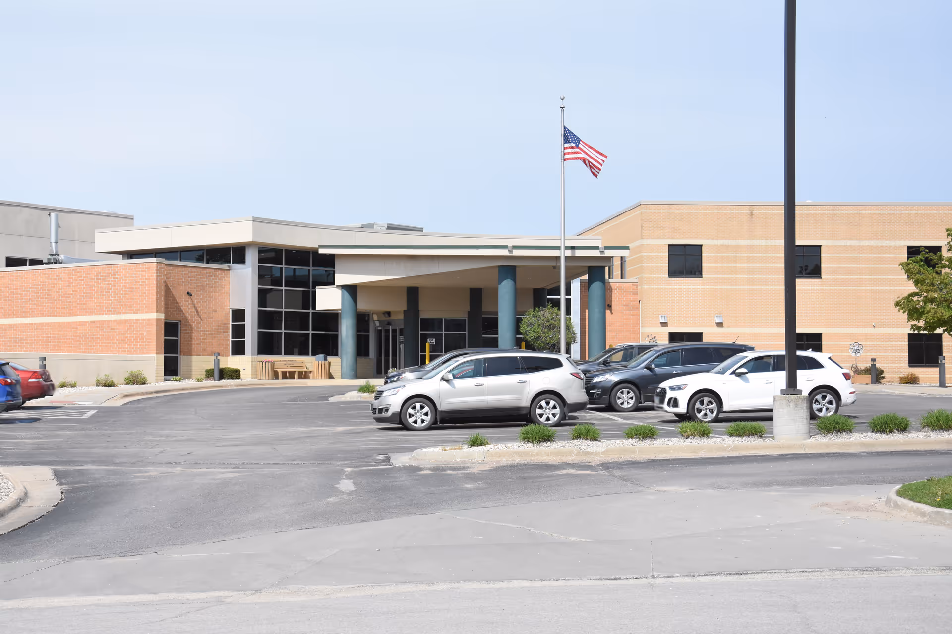 Exterior view of Veterans Memorial Hospital entrance with cars in the parking lot.