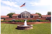 Exterior view of Church of God Home with flag, fountain, and manicured lawn.