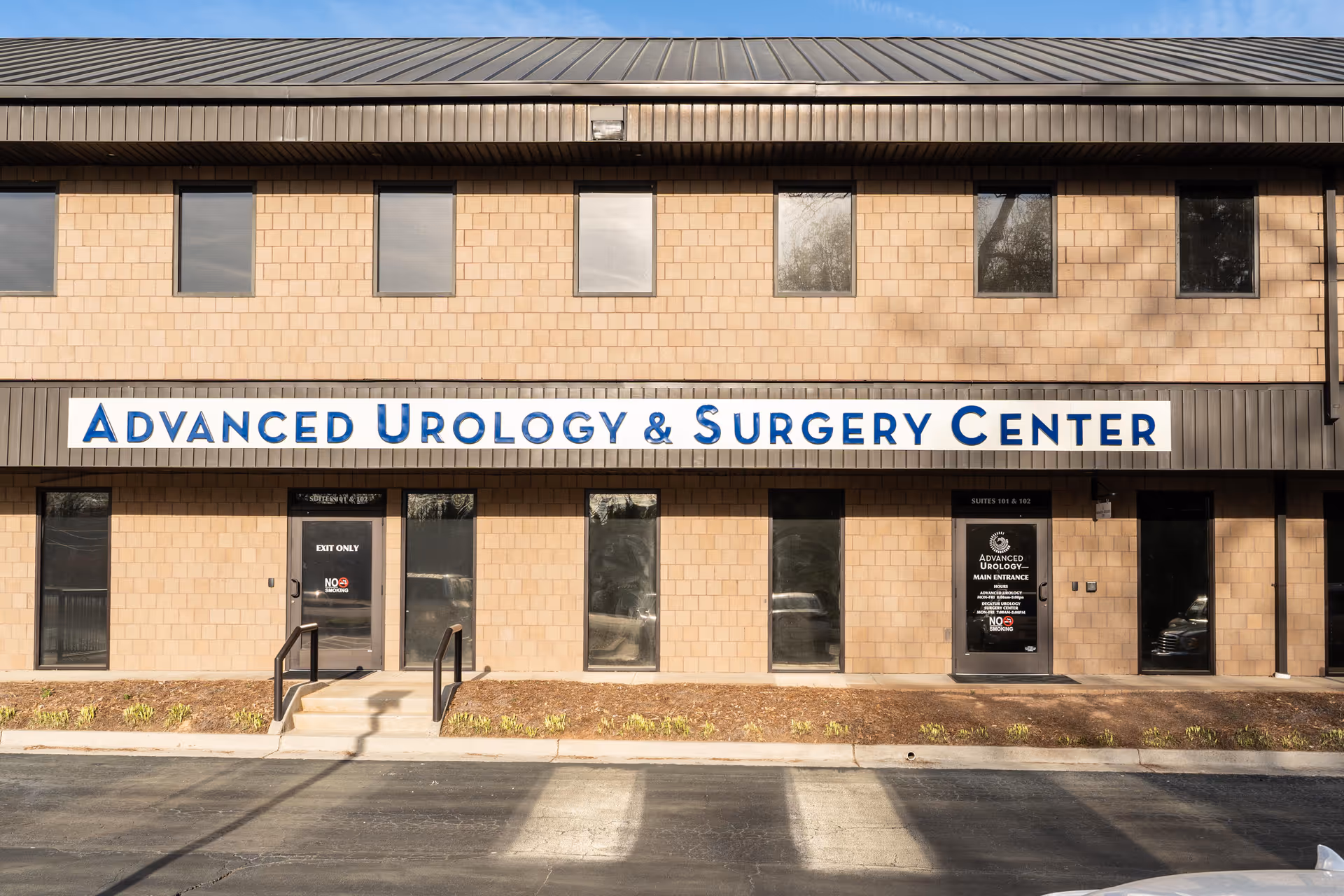 A beige brick medical building with a long blue sign reading Advanced Urology & Surgery Center.