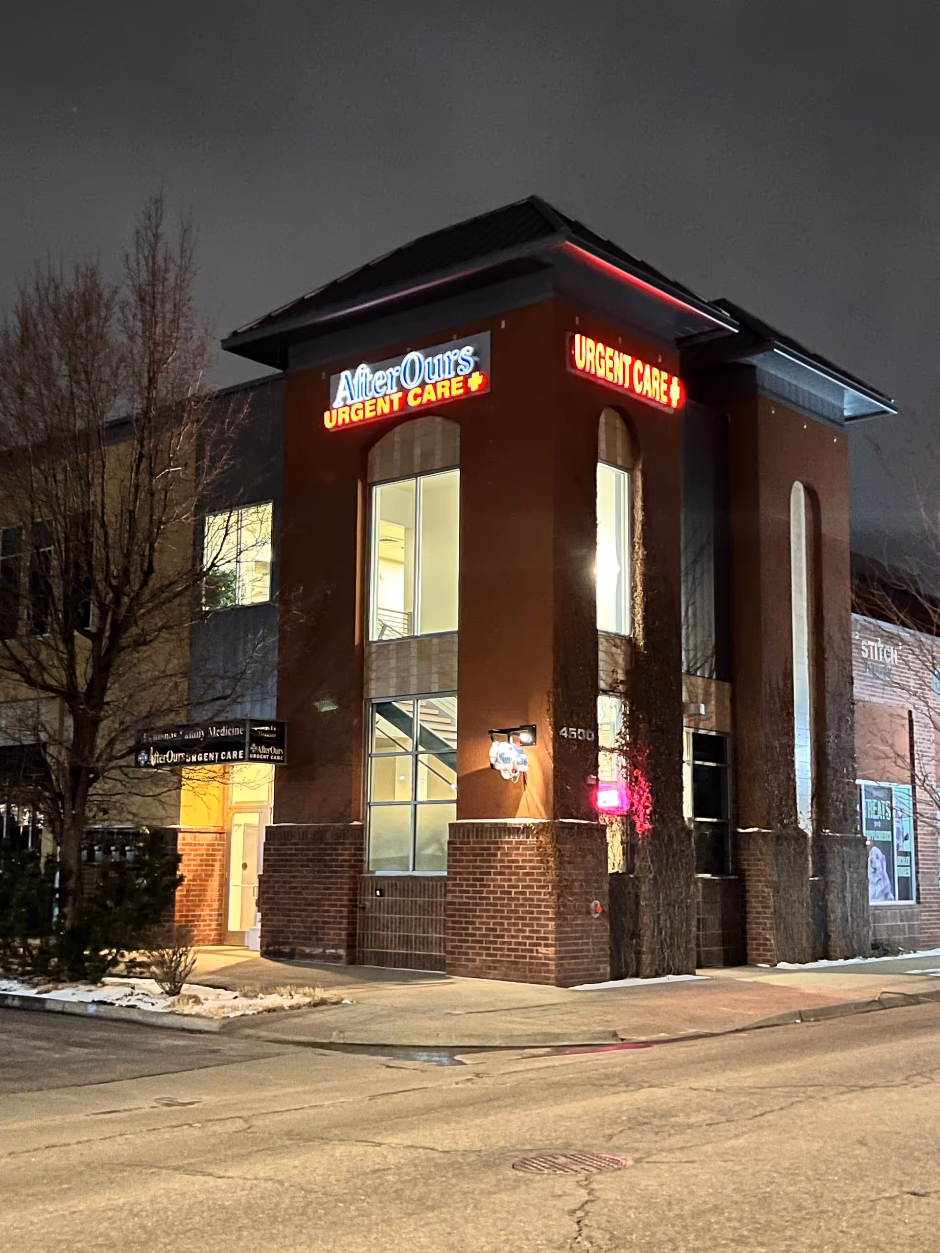 Night exterior of a brick building with illuminated AfterHours Urgent Care signage.