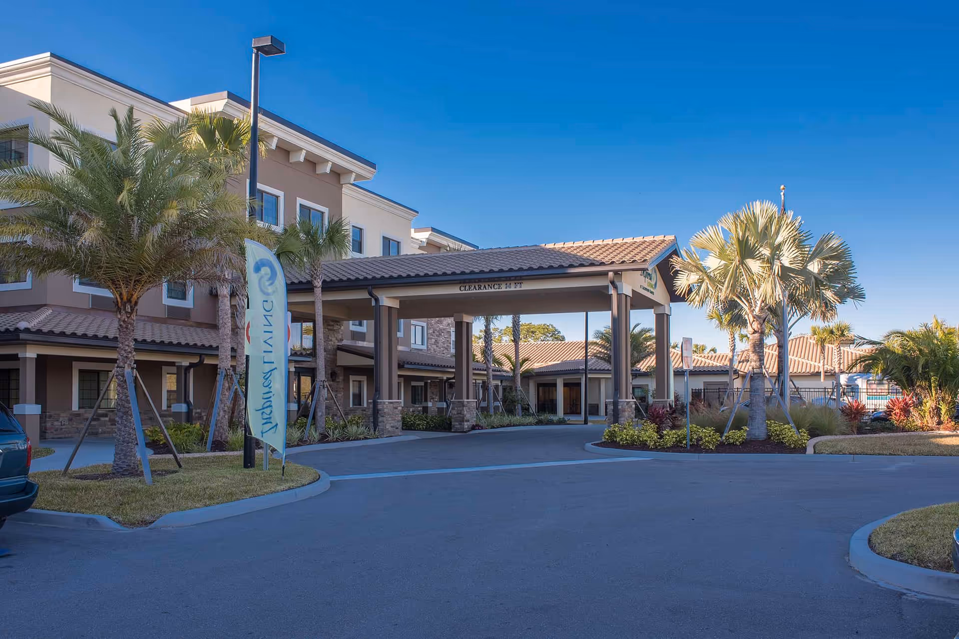Exterior view of Inspired Living Lakewood Ranch with a covered entrance and palm trees