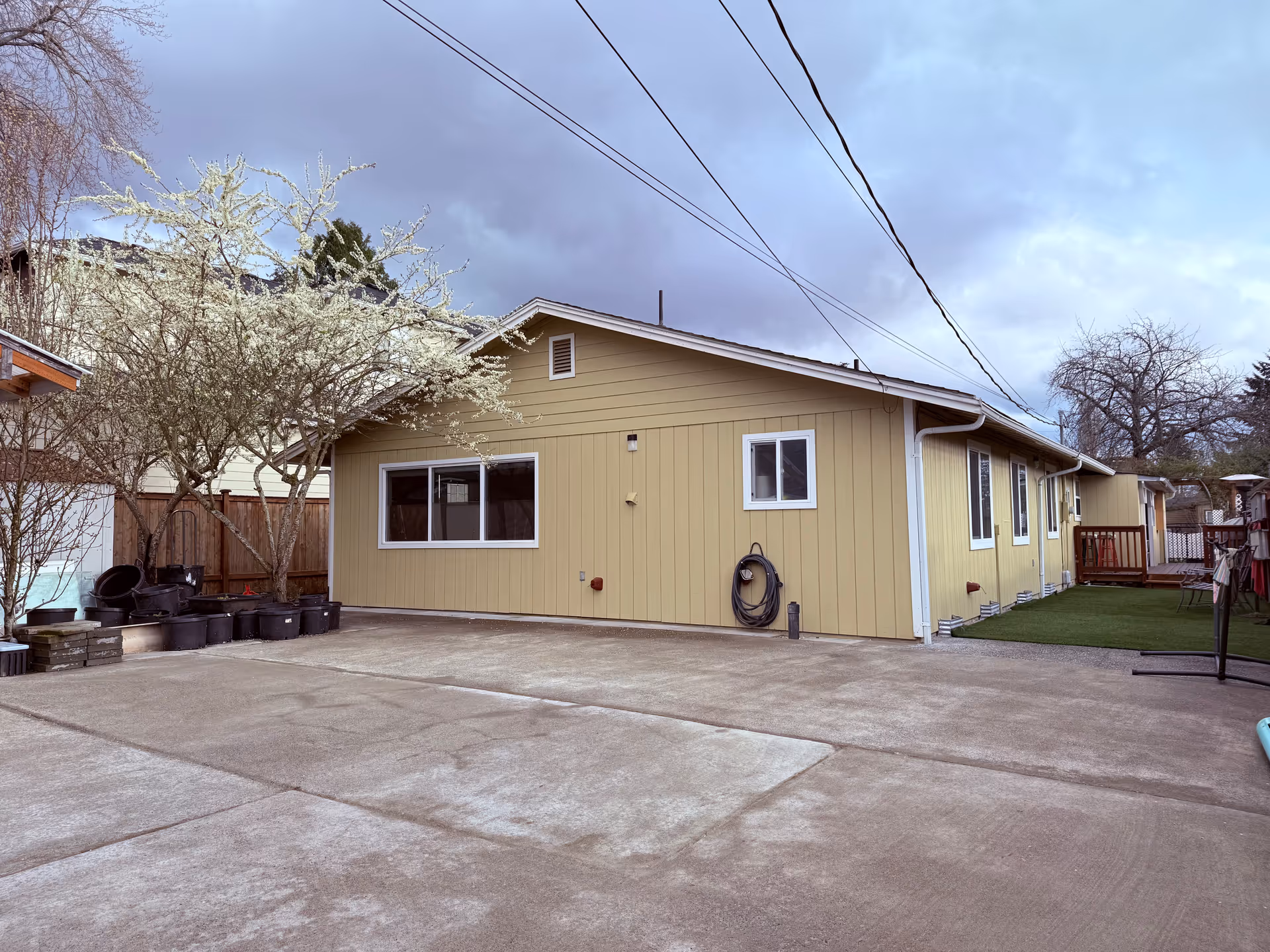Single story beige senior living facility with driveway, bare trees, and small yard.
