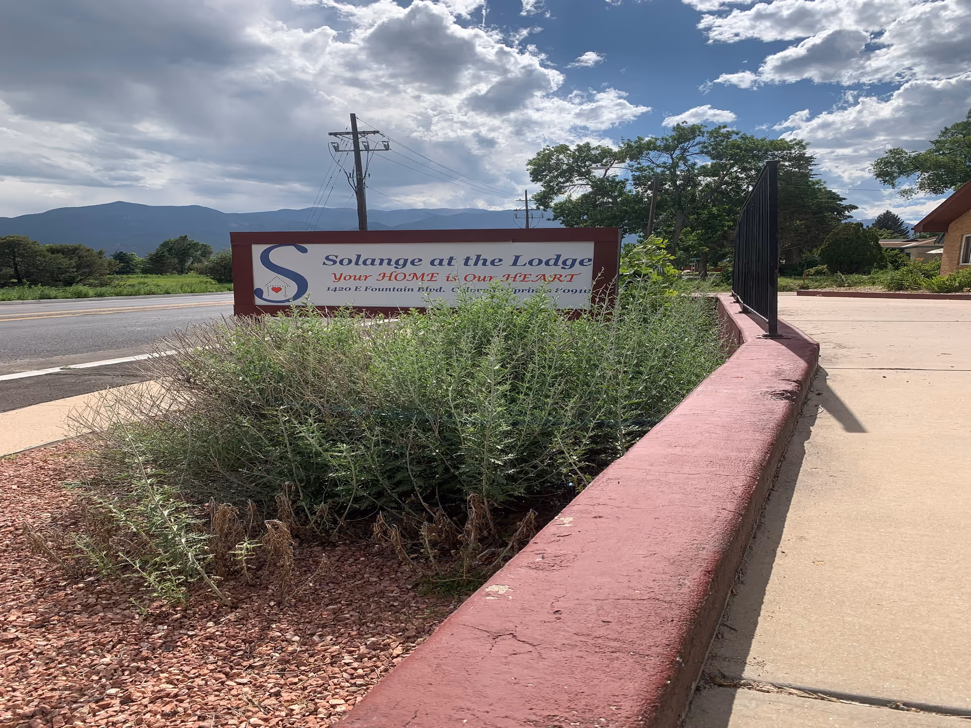 Exterior view of the Solange at the Lodge sign beside a sidewalk and shrubs.