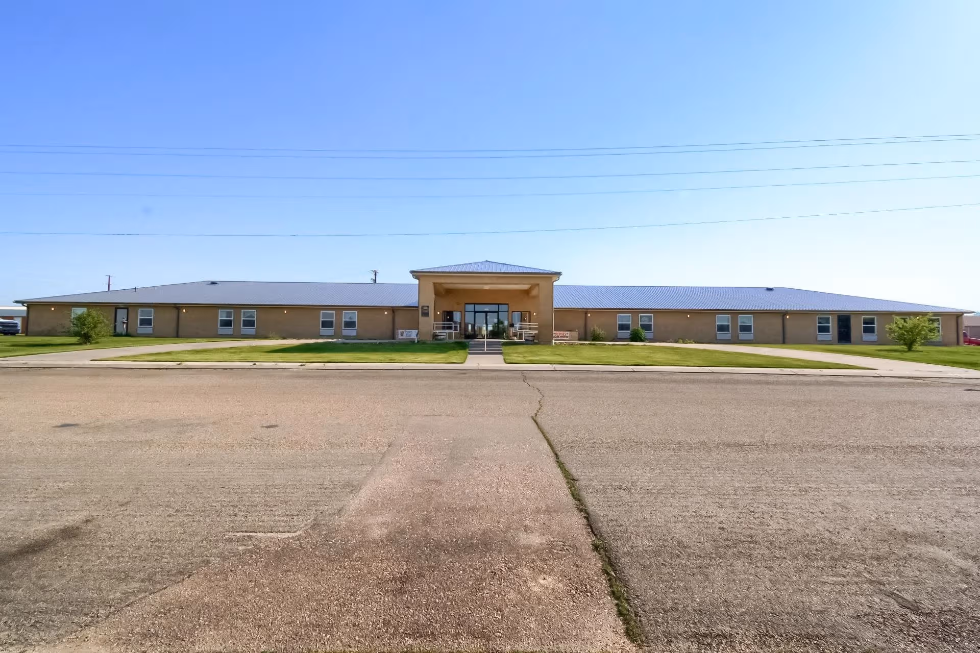 Single-story brick senior living facility with a central entrance and lawn.