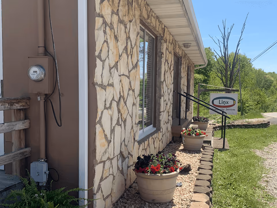 Exterior view of Linx Community Services building with stone facade and flower planters.