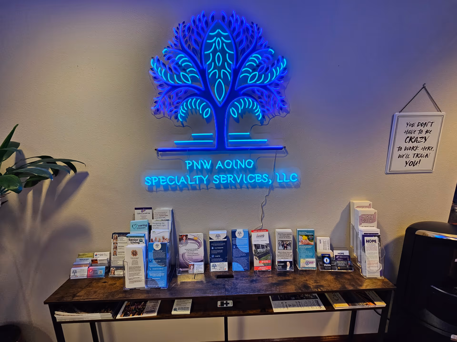 Indoor lobby area with neon tree sign and brochure-filled table